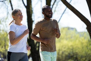 Sportif bir çift. Mutlu çift parkta birlikte koşuyor ve heyecanlı görünüyorlar.