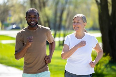 Sportif bir çift. Mutlu çift parkta birlikte koşuyor ve heyecanlı görünüyorlar.