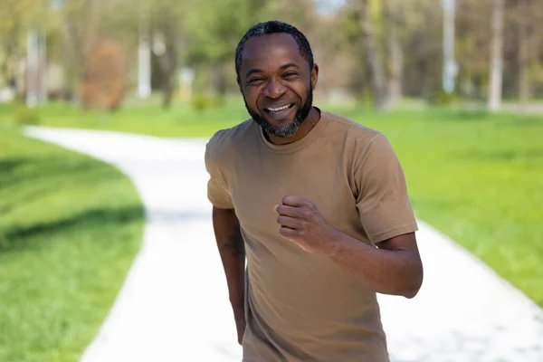 Jogging. Mature african american man jogging in the park and looking contented