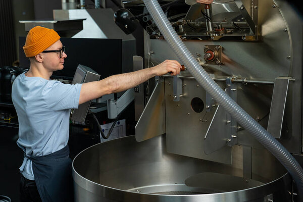 Modern coffee roasting factory, man operating process of creating coffee.