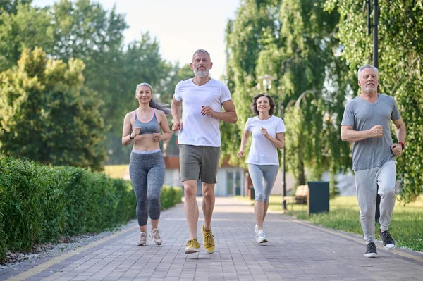 Healthy group of people jogging in park, enjoying friend time at jogging park while running.