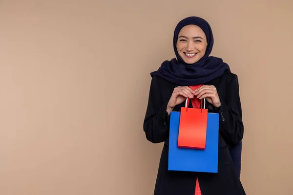 Glimlachende Moslim Vrouw Hijab Staan Met Boodschappentassen Geïsoleerd Beige Achtergrond — Stockfoto