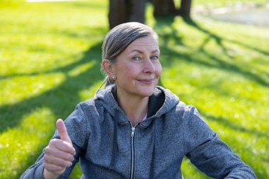 Keyfin yerinde. Yakışıklı, gülümseyen olgun bir kadın yoga minderinde oturuyor.