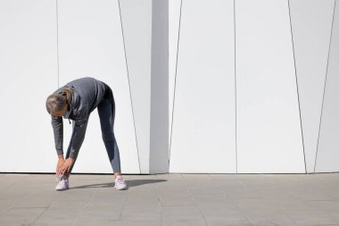 Esniyorum. Spor giyimli bir kadın egzersiz yapıyor ve esneme hareketleri yapıyor.