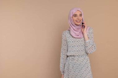 Telefon var. Pembe tesettürlü genç kadın telefonda konuşuyor.