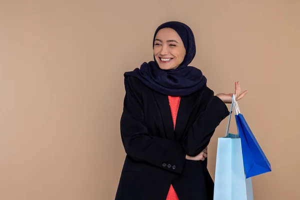 Vrolijke Moslim Vrouw Hijab Staan Met Boodschappentassen Geïsoleerd Beige Achtergrond — Stockfoto