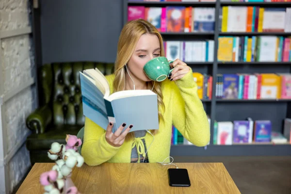 Perpustakaan Wanita Pirang Muda Minum Kopi Dengan Buku — Stok Foto