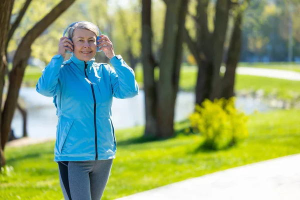 stock image In the park. Woman in blue blazer in headphones in the park