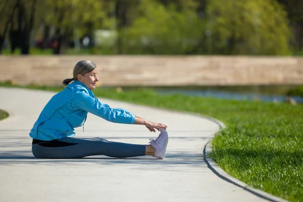 Körperstreckung Frau Sitzt Park Auf Der Yogamatte Und Macht Stretching — Stockfoto