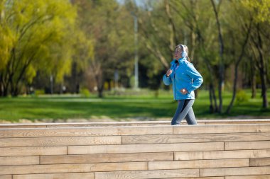 Sükunet. Sabahleyin mavi ceketli bir kadın parkta koşuyor.