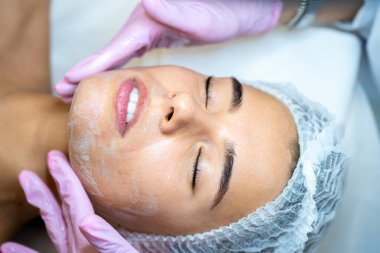 Tanınmayan kadın kozmetikçi kadınların yüzüne beyaz maske takıyor, spa prosedürleri, yüz temizleme....
