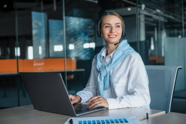 Çalışıyorum. Ofiste çalışan ve dizüstü bilgisayarda yazan genç bir kadın.