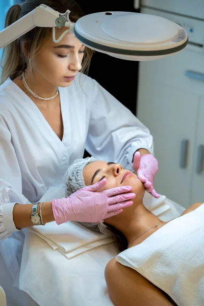 Cosmetologist Mulher Jovem Aplica Máscara Branca Cara Mulheres Procedimentos Spa — Fotografia de Stock