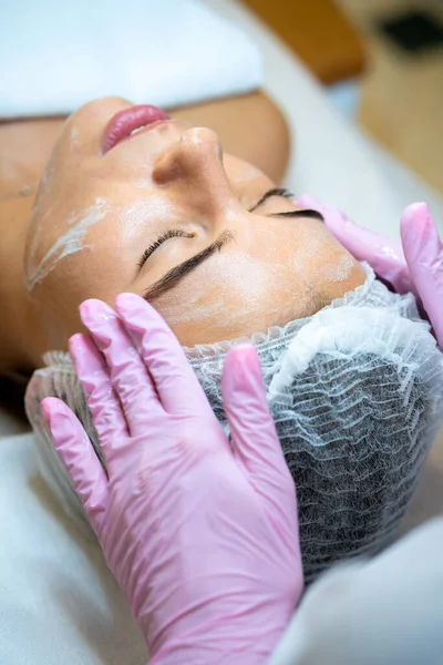 无法辨认的女性美容师在女性脸上涂上乳霜 做美容手术 — 图库照片
