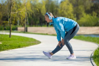 Sabah egzersizleri. Spor giyimli orta yaşlı bir kadın parkta egzersiz yapıyor.