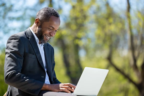Работаю Снаружи Африканский Американский Бизнесмен Работает Ноутбуке Парке Выглядит Довольным — стоковое фото