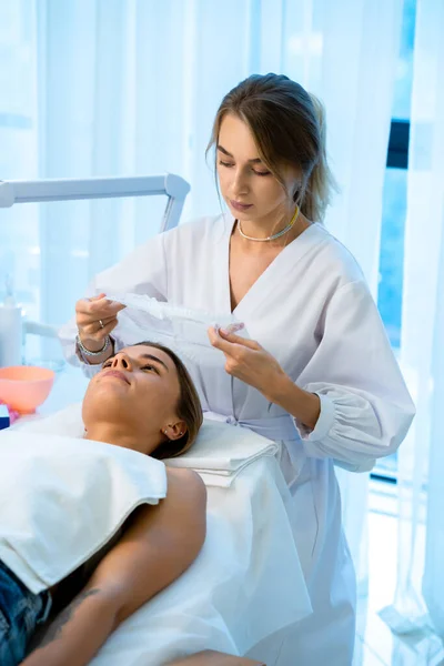 Lekarz Kosmetolog Przygotowujący Klienta Zabiegów Kosmetycznych Nakładając Jednorazową Nasadkę Głowę — Zdjęcie stockowe