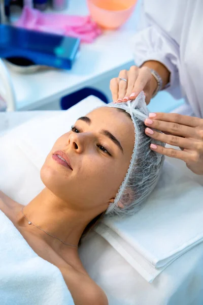 Mulher Deitada Clínica Cosmetologia Usando Chapéu Descartável Preparando Para Procedimentos — Fotografia de Stock