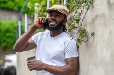 Çağrıda. Gülümseyen adam telefonda konuşuyor ve memnun görünüyor.