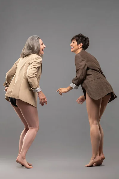 Young spirit. Two senior women in panties and jackets dancing and feeling excited