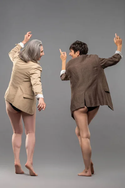 若い精神 パンツとジャケットを着た2人の先輩女性が踊って興奮しています — ストック写真