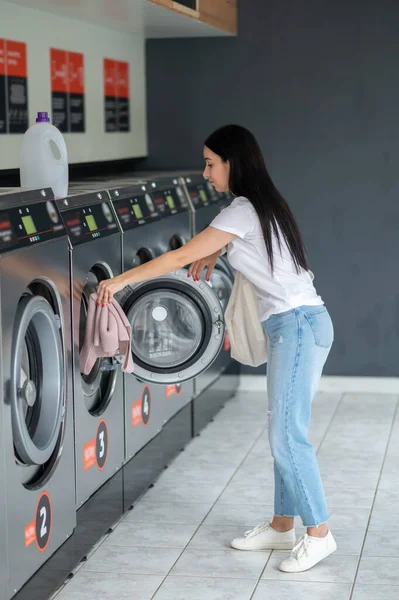 Esmer Kadın Çamaşırhanedeki Çamaşır Makinesine Kirli Çamaşırlarını Sokuyor — Stok fotoğraf