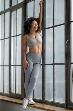 Kendine güvenen genç bir kadın. Oldukça güzel görünümlü atletik bir kadın çitin yanında duruyor.