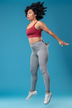 Atlıyorum. Genç, siyah saçlı, spor kıyafetli, atlayan bir kadın.