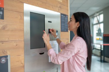 Esmer kadın otomatik otomattan kahve alıyor..