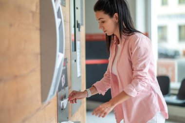 Esmer kadın otomatik otomattan kahve alıyor..