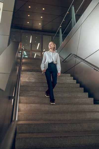В офисном центре. Стройная элегантная женщина на лестнице в офисном центре