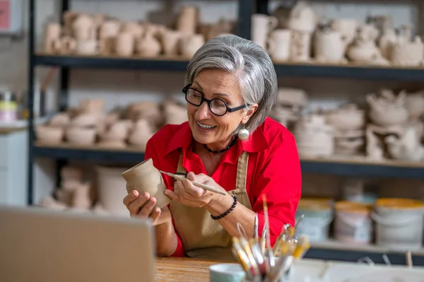Dojrzała Kobieta Malowanie Ceramiki Ceramiki Produkt Przed Laptopem Podczas Transmisji — Zdjęcie stockowe