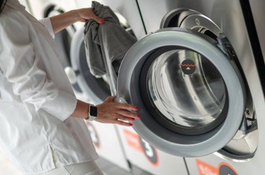 Kadın çamaşırlarını yıkamak için kamusal alanda kaliteli çamaşır makinesi kullanıyor. Kamu dairesinde çamaşır ve kurutma makinesi kullanıyor..