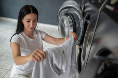 Kadın çamaşırlarını yıkamak için kamusal alanda kaliteli çamaşır makinesi kullanıyor. Kamu dairesinde çamaşır ve kurutma makinesi kullanıyor..