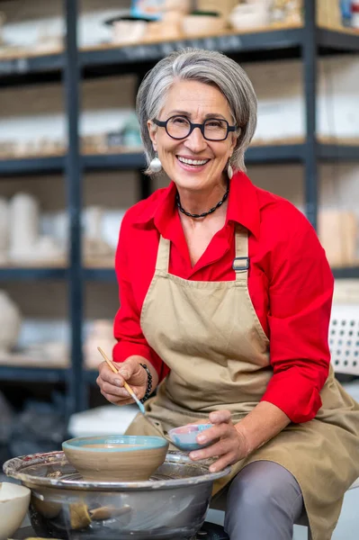 Mature Craftswoman Painting Clay Mug Blue Paint Using Pottery Wheel — Stock Photo, Image