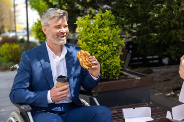 Şehir sokaklarında oturup kahve içerken ve yemek yerken takım elbise giyen iki çekici ofis arkadaşı öğle yemeği molası veriyor..