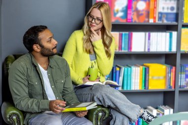 Kütüphanede. Güzel kadın ve genç adam kütüphanede oturuyor.