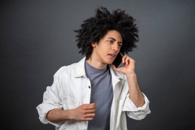 Sorunlar. Kıvırcık saçlı genç adam telefonda konuşuyor ve stresli görünüyor.