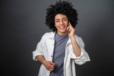 Telefon var. Beyaz gömlekli adam telefonda konuşuyor ve gülümsüyor.