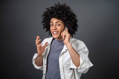 Heyecanlı. Genç siyah saçlı adam telefonda konuşuyor ve heyecanlı görünüyor.