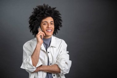 Heyecanlı. Genç siyah saçlı adam telefonda konuşuyor ve heyecanlı görünüyor.