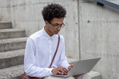 Dijital göçebe. Kıvırcık saçlı genç dijital göçebe dışarıda çalışıyor ve mutlu görünüyor.