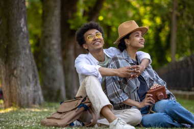 Romantik. Genç, sevimli bir çift çimenlerde oturuyor ve romantik görünüyorlar.