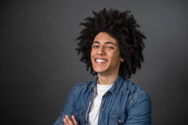 Delikanlı. Gri arka planda kıvırcık saçlı bir gencin belini kaldırın.