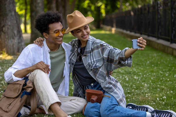 Happy moments. Cute couple sitting on the grass in the park and making selfie
