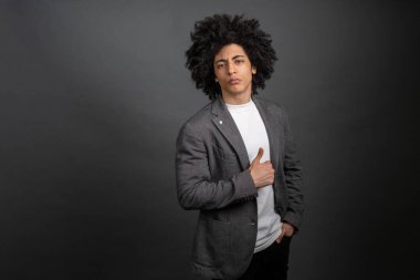 Şık bir adam. Gri ceketli, koyu renk saçlı, memnun bir genç.