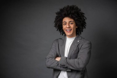 Kendine güven. Gri ceketli genç adam kendine güveni tam duruyor.