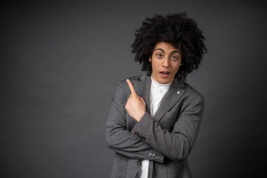 Dikkat! Genç adam gri arka planda duruyor ve bir yeri işaret ediyor.