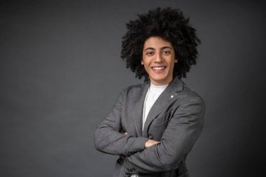 Kendine güven. Gri ceketli genç adam kendine güveni tam duruyor.