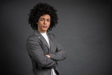 Kendine güven. Gri ceketli genç adam kendine güveni tam duruyor.